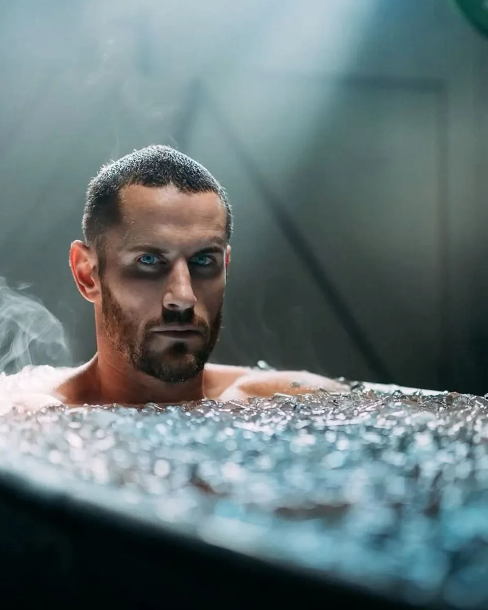 Luchador sumergido en un baño de hielo tras el entrenamiento, con luz fría
